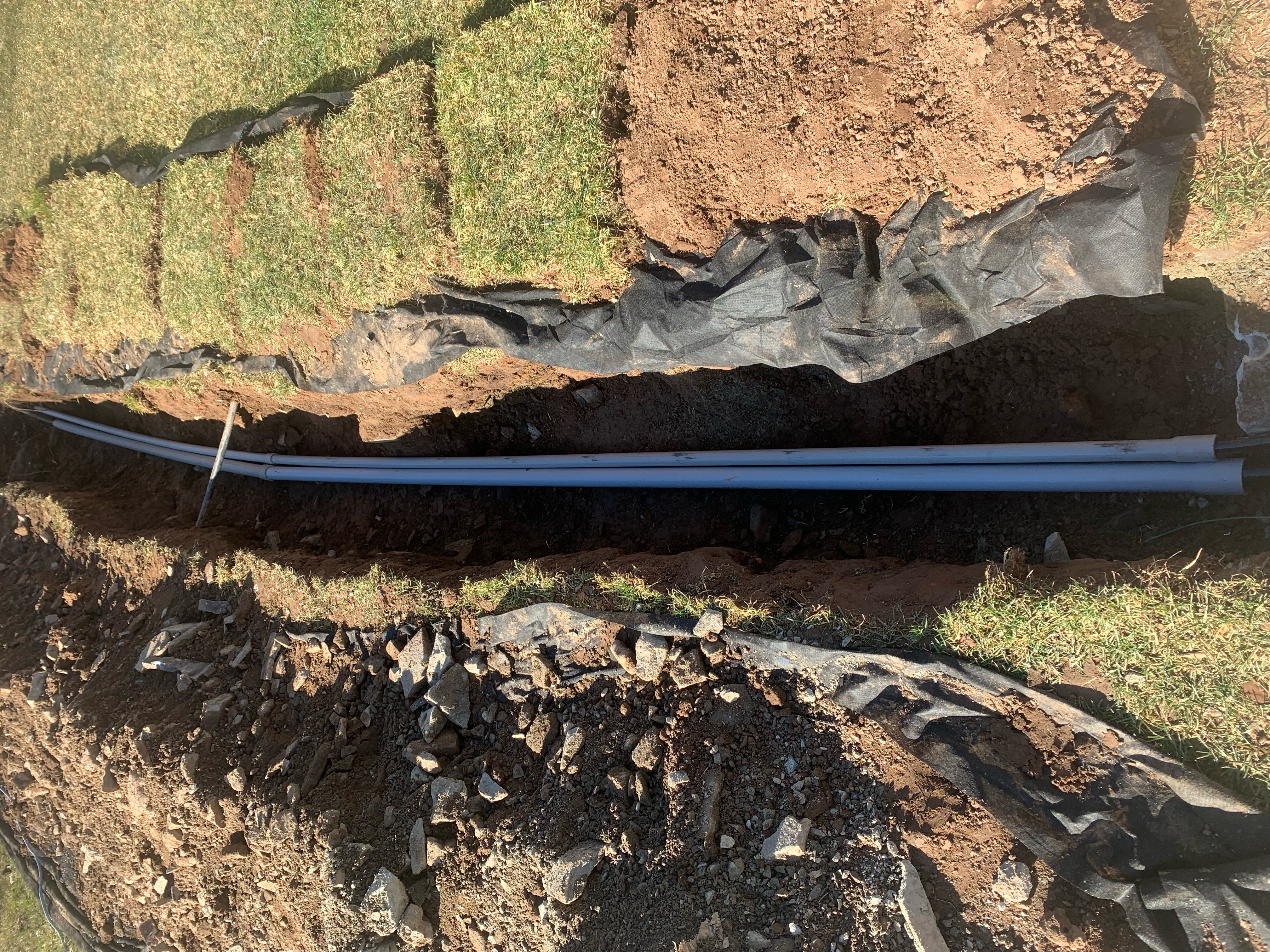 Here Henderson Electrical uses landscape paper and tarps to meticulously preserve grass during a new underground cable installation through an existing garden.